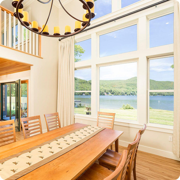 large wood dining table looking out windows over a lake